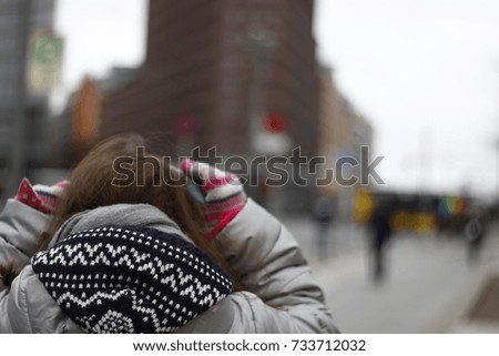Girl with her Hand on her Head for Winter Cold or Worries. Berlin City in Background