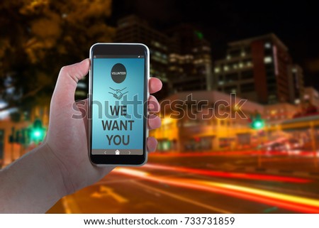 Cropped hand holding mobile phone against illuminated roads by building in city
