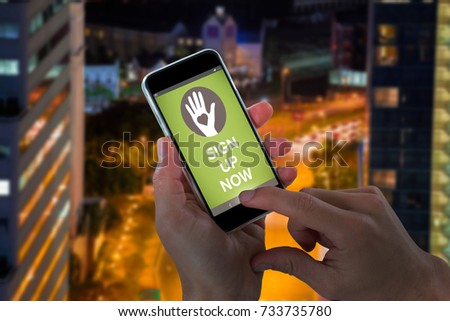 Close-up of cropped hands holding mobile phone against illuminated road amidst building at night