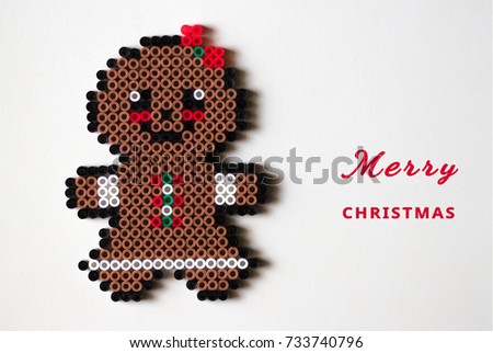 A little gingerbread man's wife with white skirt coloring  made from mini beads ornament decorated on cream background with space for text.Concept Merry Christmas.Top view, flat lay.Selective focus.