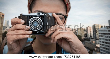 Close up of woman photographing with camera against city against blue sky