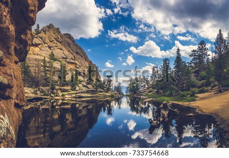 Perfectly still water on Gem Lake with reflection of blue sky, clouds, mountains, and trees, Estes Park, Colorado Royalty-Free Stock Photo #733754668