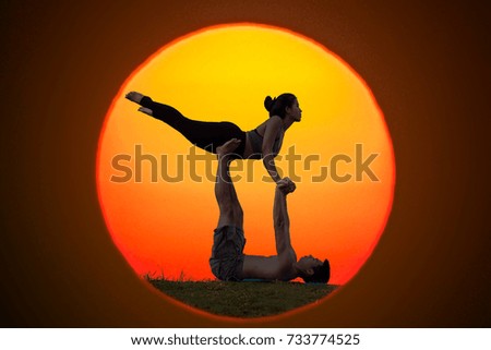 Silhouette couple practicing yoga at sunrise.