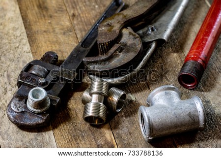 Hydraulics, tools for plumber on wooden table. Workshop, table and tools - adjustable spanner, connectors, keys. Black background