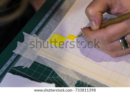 The specialist performs coloring of the drawing with watercolor.