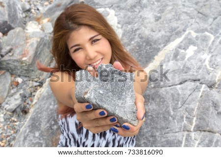 Young woman holding rock heart shape, symbol of love. sweet valentine day. Asian girl showing heart give to you, looking at you. loving sign. selective focus on heart rock. happy positive attitude.