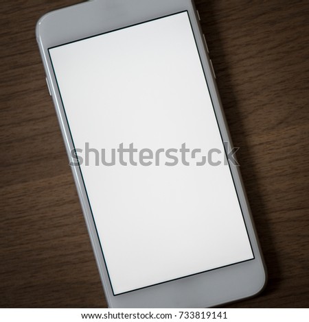 Using smartphone on wooden table, Mobile white screen with Space for text or design. business and technology background