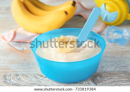 Plastic bowl with porridge for baby on wooden background Royalty-Free Stock Photo #733819384