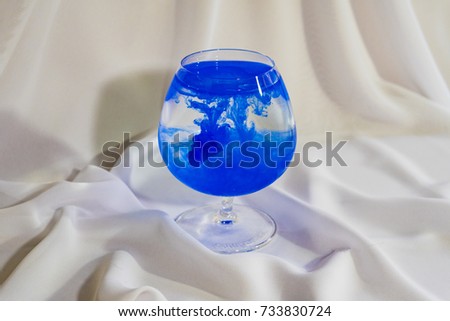 Blue watercolor in a glass. Color mix in the glass. Oil paint in water.