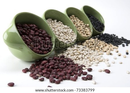 Assorted mixed dried beans spilling in green ceramic dish