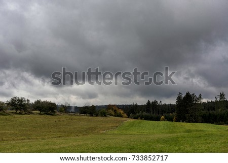 storm clouds, racing over the green meadows to the autumn forest