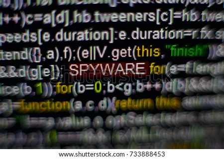 Macro photo of computer screen with program source code and highlighted SPYWARE inscription in the middle. Script on the screen with virus in it. Cyber security concept. Technology background
