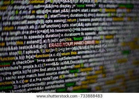Macro photo of computer screen with program source code and highlighted ERASE YOUR HARD DRIVE inscription in the middle. Script on the screen with virus in it. Cyber security concept. Technology
