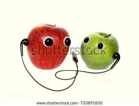Red and green small apple with cute eyes and headphones on white background. Conceptual photo. 