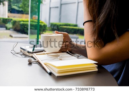 Asian girls sit in small coffee shops while drinking coffee and memorize their diary.