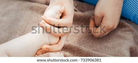  The panorama of baby feet in mother hands. Tiny newborn baby feet, concept of happy family. Fake color and toned image