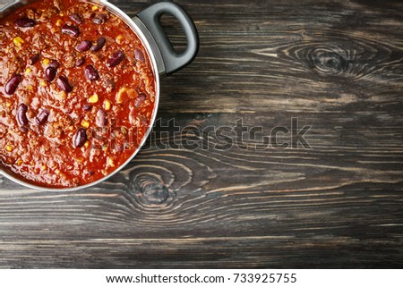 Saucepan with delicious chili con carne on wooden background Royalty-Free Stock Photo #733925755