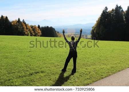 Happy woman nearby a hiking path, view to a beautiful autumnal landscape, Alpine Upland, Bavaria - back lighting picture with sun spot