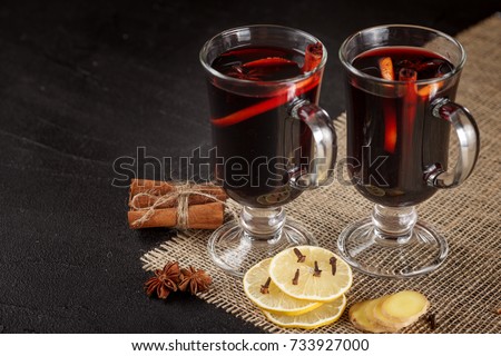 Mulled wine banner with glasses of hot red wine and spices on dark background. Closeup photography of warm alcohol drink in modern dark mood style.