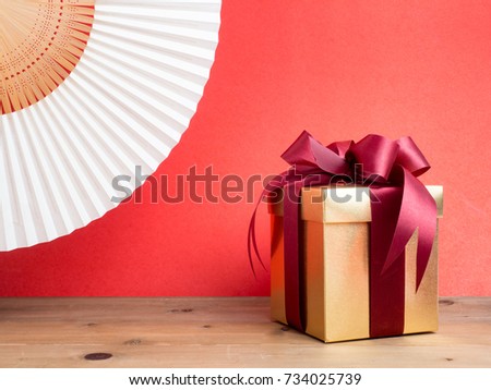 Gold gift box with red ribbon. Red background for create idea copy space.
