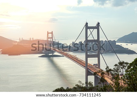 silhouette Tsing Ma double-decked suspension bridge between Ma Wan island and Tsing Yi island in Hong Kong, China at sunset and flare