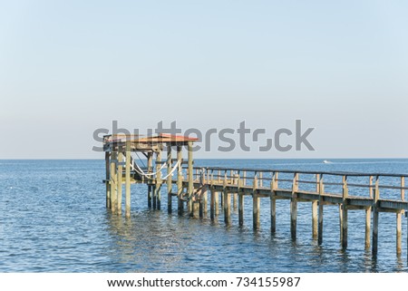 Wooden fishing piers stretching out over Galveston Bay in Kemah, Texas, USA. Foot pier for saltwater fishing of vacation home/beach house rental/bay home in Lighthouse District waterfront at sunset