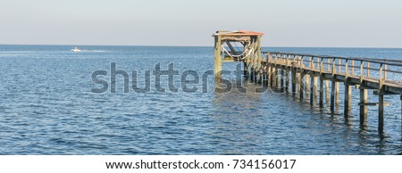 Fishing piers stretching out over Galveston Bay in Kemah, Texas, USA. Foot pier for saltwater fishing of vacation home/beach house rental/bay home in Lighthouse District waterfront at sunset. Panorama