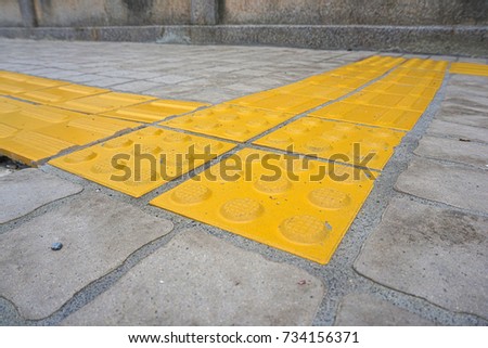 Footpath with embossed yellow tiles to help visually impaired people walking through, go in the right direction and safe life.