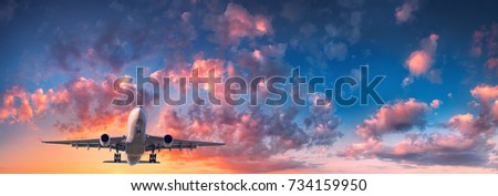 Airplane and beautiful sky. Landscape with passenger airplane is flying in the blue sky with red, purple and orange clouds at sunset. Travel. Passenger airliner. Commercial aircraft. Private jet