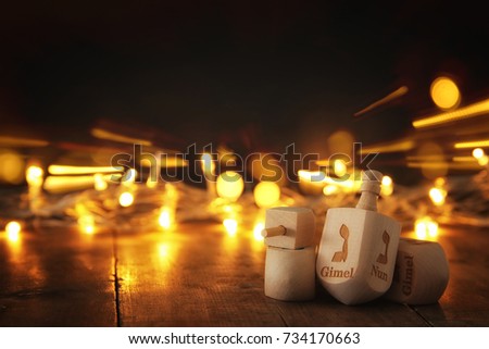 Image of jewish holiday Hanukkah with wooden dreidels colection (spinning top) and gold lights on the table