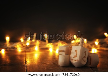 Image of jewish holiday Hanukkah with wooden dreidels colection (spinning top) and gold lights on the table