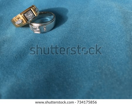 White gold and gold ring on blue background