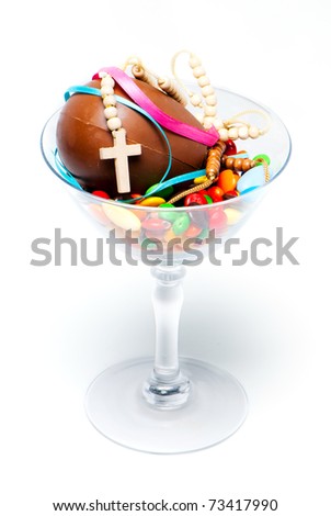 easter chocolate egg , sweets and cross in a glass on a light background