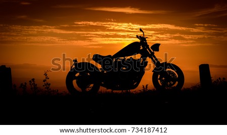 A silhouette of a custom made chopper against a colourful sunset, England, UK Royalty-Free Stock Photo #734187412