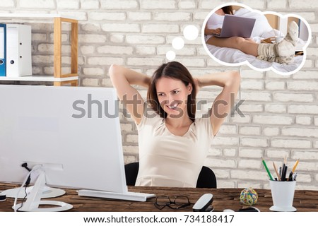 Happy Young Woman At Desk Imagining To Use Laptop While Having Breakfast On Bed