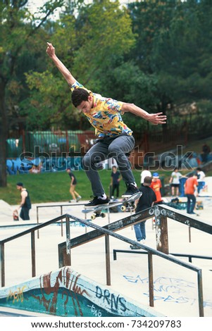 urban skater doing tricks on the ramp and railing in skatepark / young skateboarder training on the skate park in railing