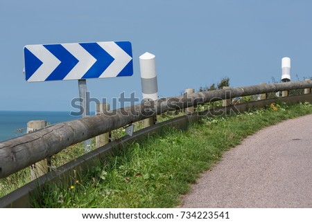 Country road with wooden crash barrier and traffic sign near coast of Normandy, France