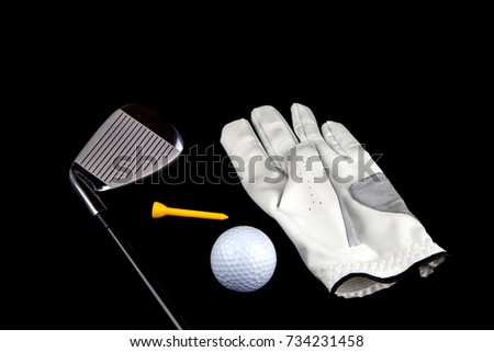 Golf club with glove ball and tee peg on a black background