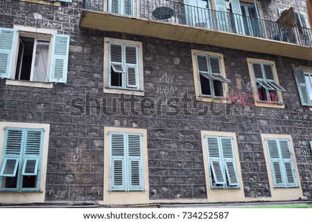 Windows of a house in France through a glass. Reflection of bar signs.
