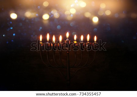 Low key abstract image of jewish holiday Hanukkah background with menorah (traditional candelabra) and burning candles.