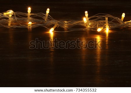 Christmas warm gold garland lights on black wooden background