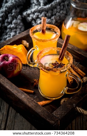Halloween, Thanksgiving. Traditional autumn, winter drinks and cocktails. Spicy hot pumpkin sangria, with apple, cinnamon, anise. In tray, rustic wooden table, glass mugs. Selective focus copy space