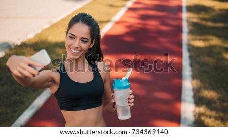 An attractive female runner taking selfie outside.
