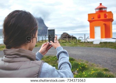 Woman taking photo of lighthouse in vacation in Iceland