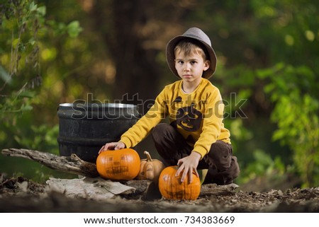 Little boy in Halloween costume with pumpkins in the forest