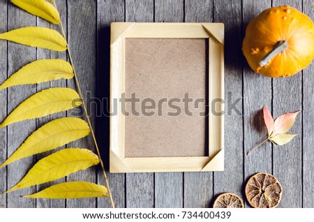 Autumn inspiration and decoration with mini pumpkin, orange, leaves and photo frame for picture on wooden background. Above view. Concept