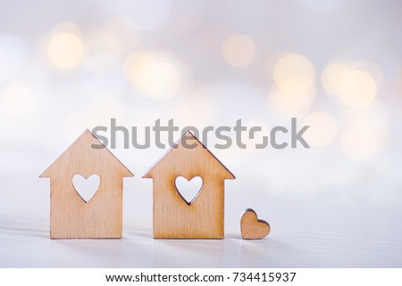 Two wooden houses with hole in the form of heart with little heart on light bokeh background. Romantic card. Concept of sweet home. 
