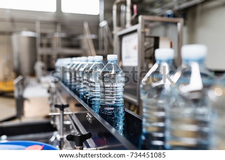 Bottling plant - Water bottling line for processing and bottling carbonated water into blue bottles. Selective focus.  Royalty-Free Stock Photo #734451085