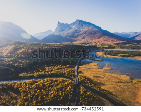 Classic norwegian scandinavian summer mountain landscape view with road, mountains and fjord with a blue sky, northern Norway, Finnmark County, shot from drone