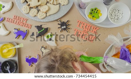 Step by step. Mother and daughter decorating Halloween sugar cookies with colorful royal icing.